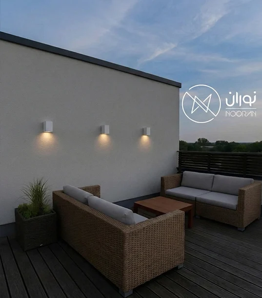 سه عدد چراغ دیواری مربعی کوچک سفید مدل H130-1 نصب شده به صورت ردیفی روی دیوار سفید تراس مدرن با نور آفتابی ملایم در هنگام عصر.