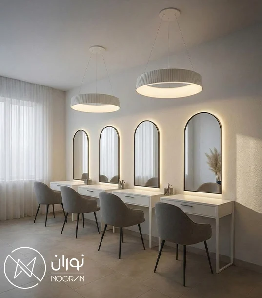 دو عدد چراغ آویز دایره‌ای بزرگ سفید مدل C44 با طراحی مینیمال و نور آفتابی، نصب شده بالای میزهای آرایش و آینه‌های گنبدی در یک سالن زیبایی مدرن.